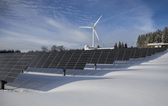 Painéis solares e turbina eólica em campo nevado