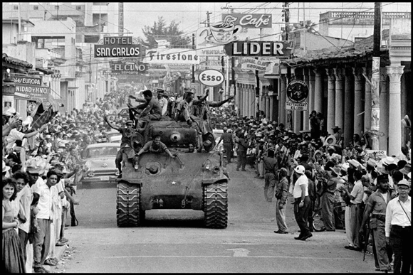 Blindado avançando por rua de cidade cubana durante a Revolução Cubana, com população nas calçadas - Duvid Geografia