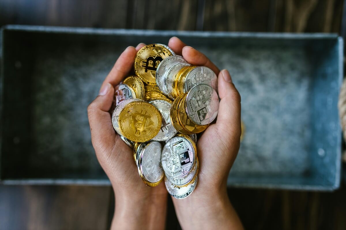 Foto de uma mão segurando moedas de bitcoin